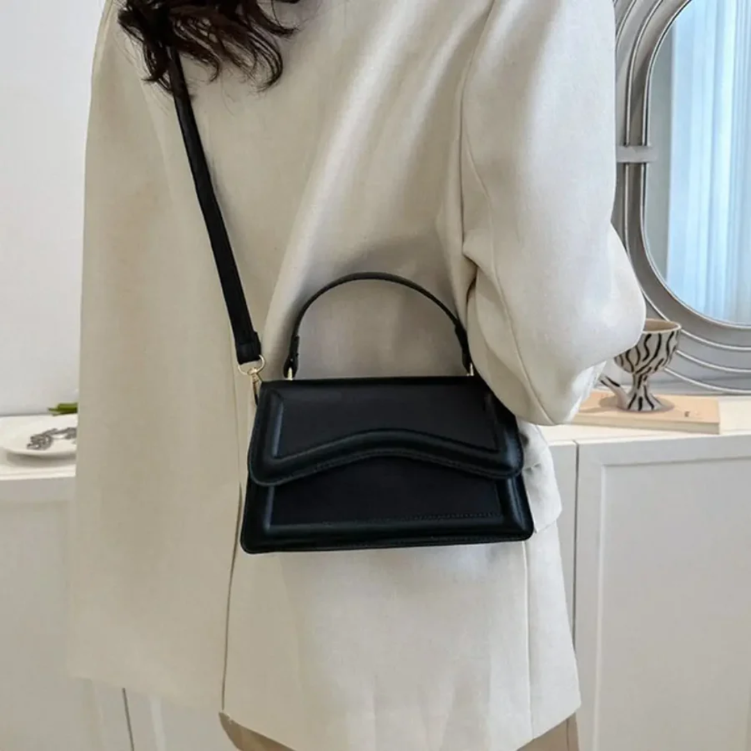Frau mit schwarzer Lederhandtasche, Umhängetasche, elegantes Design, modisches Accessoire.