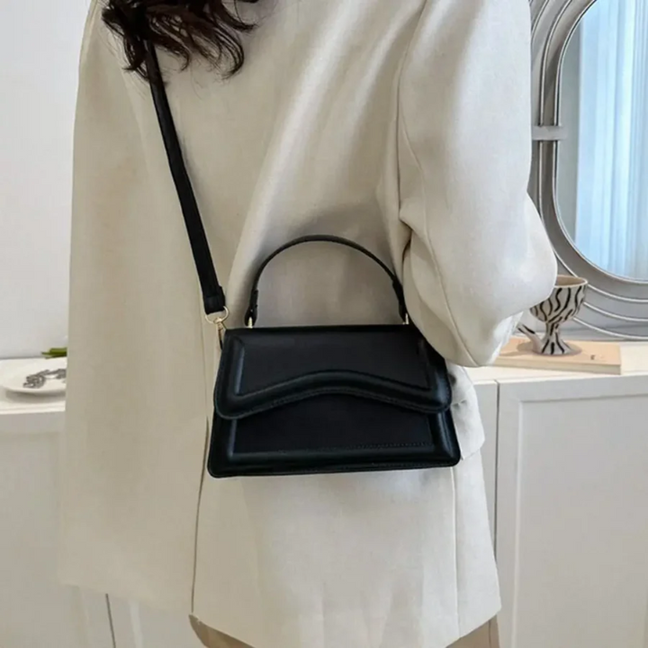 Frau mit schwarzer Lederhandtasche, Umhängetasche, elegantes Design, modisches Accessoire.