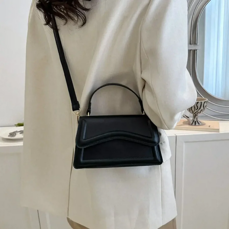 Frau mit schwarzer Lederhandtasche, Umhängetasche, elegantes Design, modisches Accessoire.
