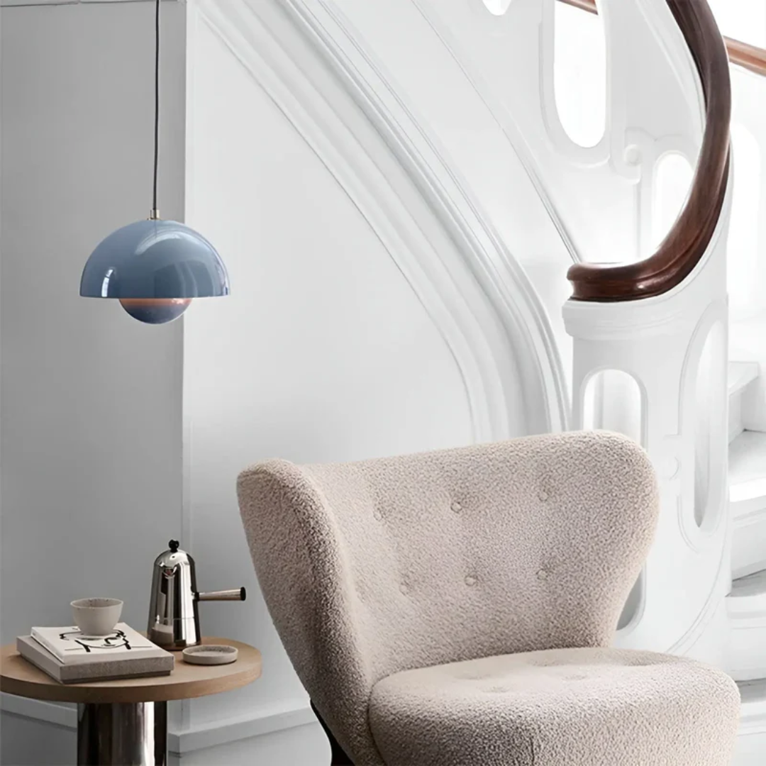 Blaue Pendelleuchte, cremefarbener Sessel, modernes Interieur, skandinavisches Design.