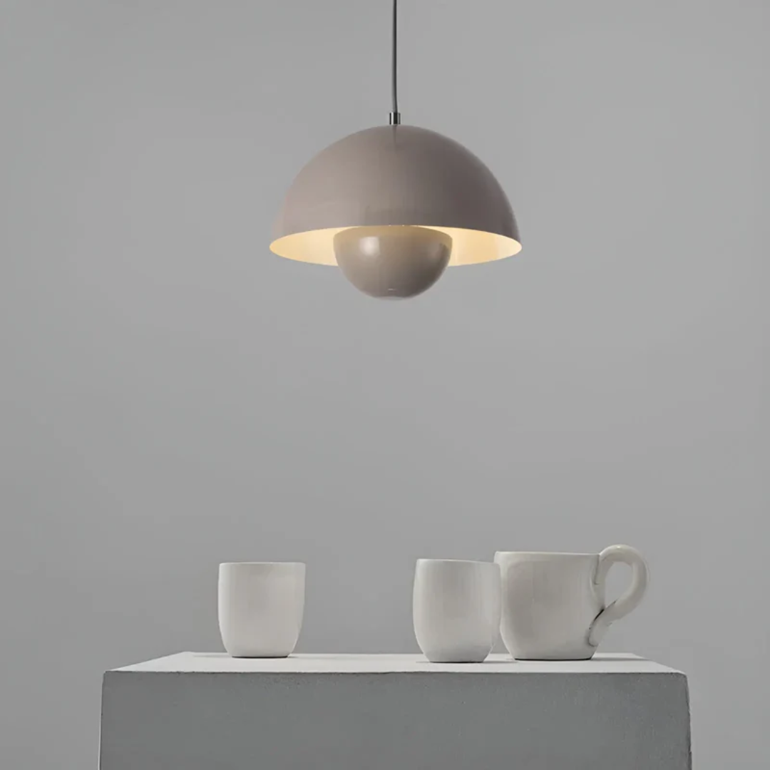Graue Hängelampe über Tisch mit weißen Keramiktassen, modernes minimalistisches Design.