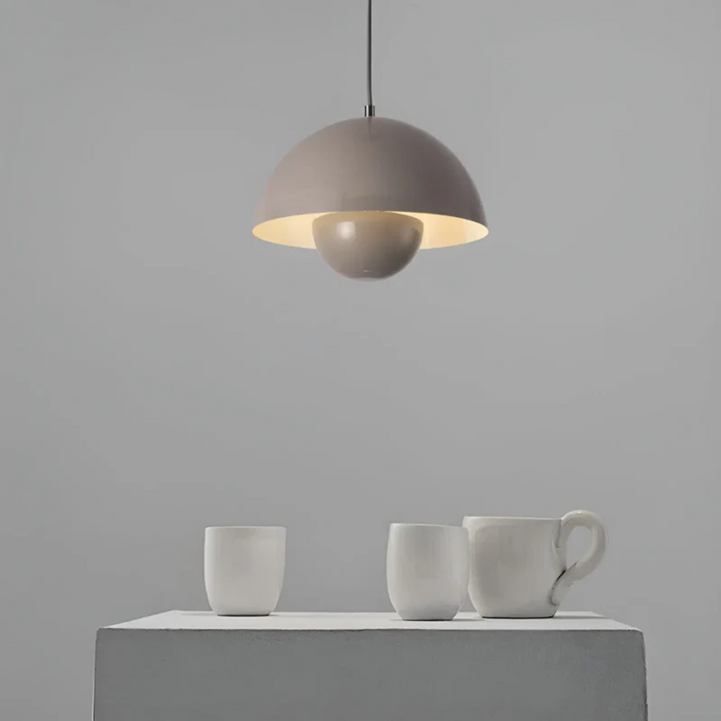 Graue Hängelampe über Tisch mit weißen Keramiktassen, modernes minimalistisches Design.