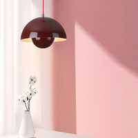 Rote Pendelleuchte im modernen Design vor rosa Wand, weiße Vase mit Blumen, minimalistisches Interieur.