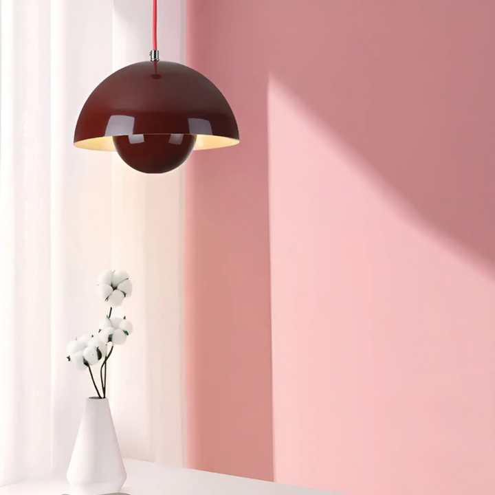 Rote Pendelleuchte im modernen Design vor rosa Wand, weiße Vase mit Blumen, minimalistisches Interieur.