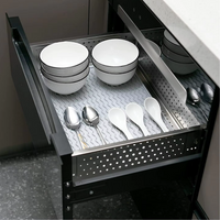 Offene Küchenschublade mit weißen Schalen und Löffeln auf rutschfester Matte.