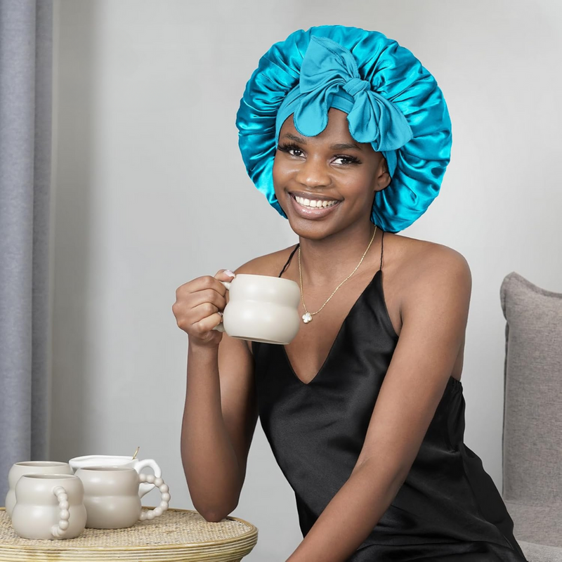 Frau mit blauem Satin-Bonnet und schwarzem Kleid hält Tasse, lächelnd, moderne Inneneinrichtung.