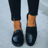 Schwarze Damen-Loafer aus Leder mit Krokodilprägung, elegant und modern, auf Gehweg.