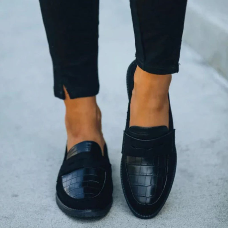 Schwarze Damen-Loafer aus Leder mit Krokodilprägung, elegant und modern, auf Gehweg.