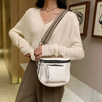 Frau mit weißer Umhängetasche, cremefarbenem Pullover, brauner Hose, modisch, elegant.