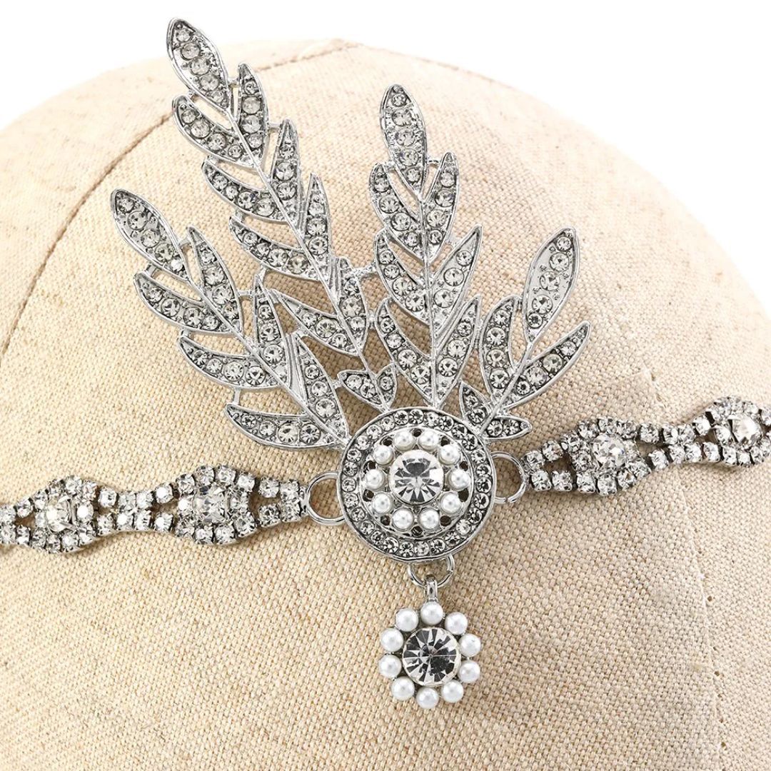 Silberne Strass-Haarspange mit Blattdesign und Perlenverzierung auf beigem Hintergrund.