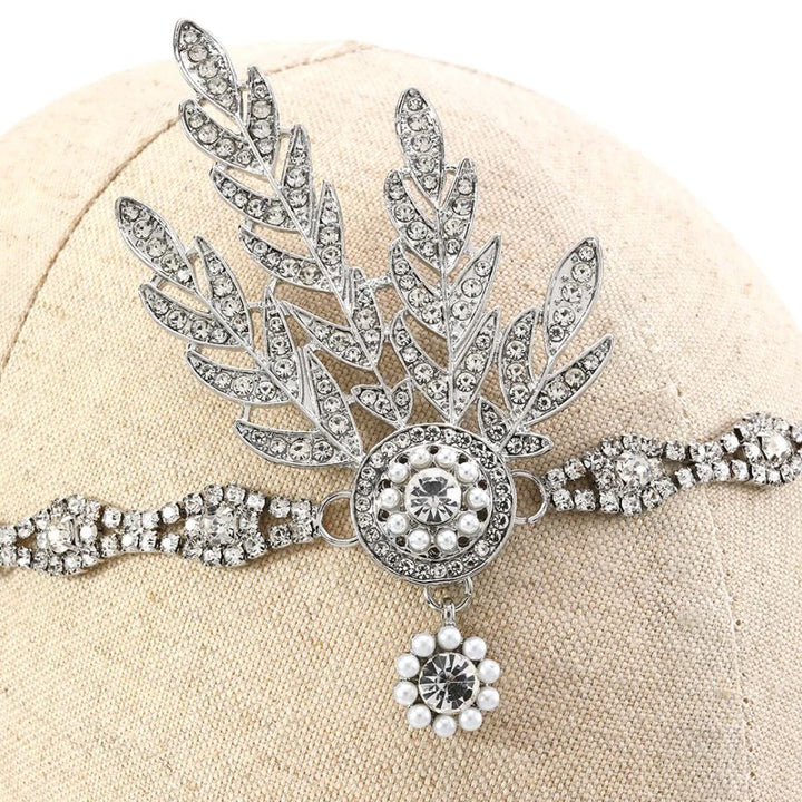 Silberne Strass-Haarspange mit Blattdesign und Perlenverzierung auf beigem Hintergrund.