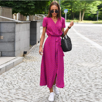 Frau in pinkem gepunktetem Kleid, Sonnenbrille, weiße Sneaker, schwarze Tasche, Sommermode.