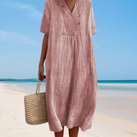 Frau im rosa Leinenkleid am Strand mit Strohtasche, Sommermode, Strandkleidung.