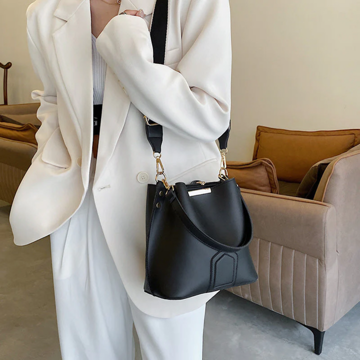 Frau in weißem Anzug mit schwarzer Lederhandtasche, elegantes Design, modisch, modern.