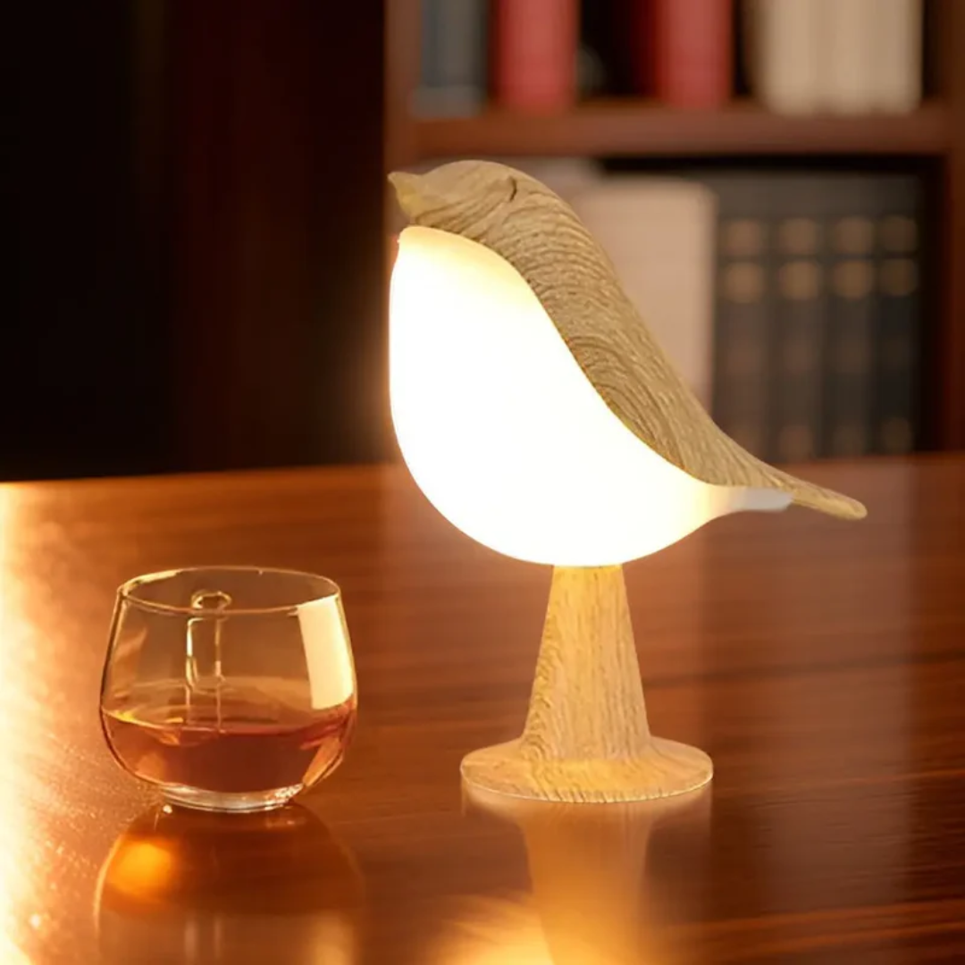 Holz-Vogel-Tischlampe mit warmem Licht neben Glas auf Holztisch, dekorative Beleuchtung.