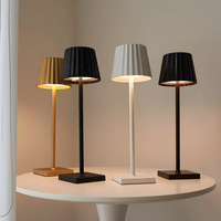 Vier moderne Tischlampen in Gold, Schwarz, Weiß und Braun auf rundem Tisch, minimalistisches Design.