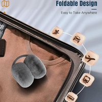 Faltbare graue Ohrenschützer auf braunem Pullover im Koffer, ideal für Reisen.