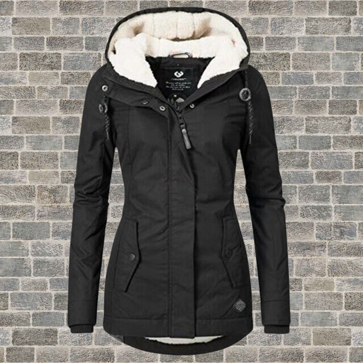 Schwarze Damen-Winterjacke mit Kapuze, Fleece-Futter, Reißverschluss, vor Ziegelwand.