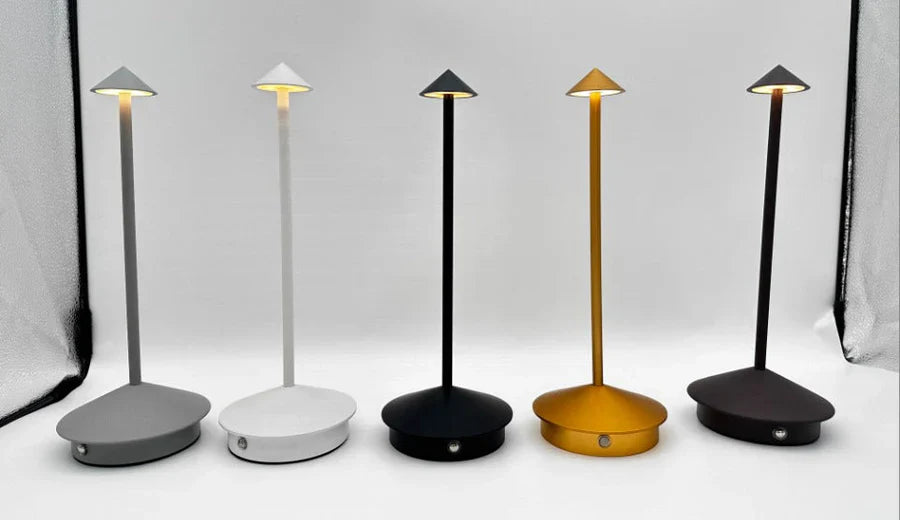 Fünf moderne LED-Tischlampen in Grau, Weiß, Schwarz, Gold und Braun auf weißem Hintergrund.
