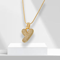 Goldene Y-förmige Halskette mit Strasssteinen auf weißem Podest, eleganter Schmuck.