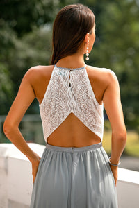 Frau in weißem Spitzenoberteil und grauem Rock, Rückansicht, elegantes Sommeroutfit.