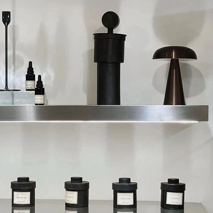 Moderne schwarze Duftkerzen und Aromaflaschen auf Metallregal, minimalistische Dekoration.