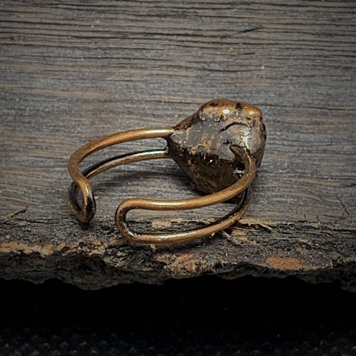 Antiker Bronze-Ring mit rustikalem Design auf Holzoberfläche, handgefertigter Schmuck.