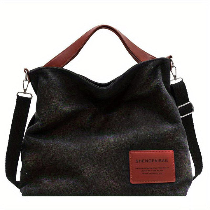 Schwarze Canvas-Schultertasche mit braunen Griffen, lässig, modisch, vielseitig.