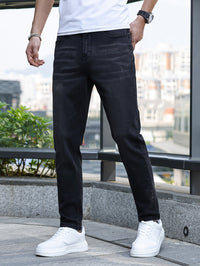 Mann in schwarzer Jeans und weißen Sneakers, lässiger Stil, urbaner Hintergrund.