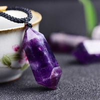 Amethyst-Anhänger an schwarzer Kordel, lila Kristall, Schmuck, Heilstein, Nahaufnahme.