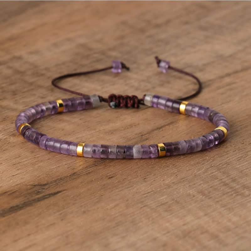 Lila Amethyst-Armband mit goldenen Akzenten, verstellbar, handgefertigt, auf Holzoberfläche.