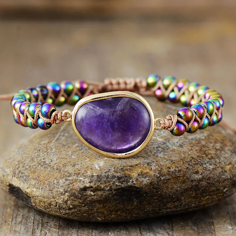 Armband mit lila Amethyst und bunten Perlen, handgefertigt, auf Steinuntergrund.
