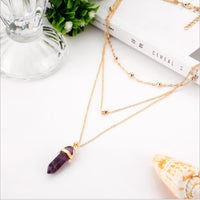 Goldene Halskette mit Amethyst-Anhänger auf weißem Hintergrund, Schmuck, Modeaccessoire.