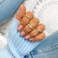 Damenhand mit goldenen Ringen, modisches Accessoire, elegantes Design, Nahaufnahme.