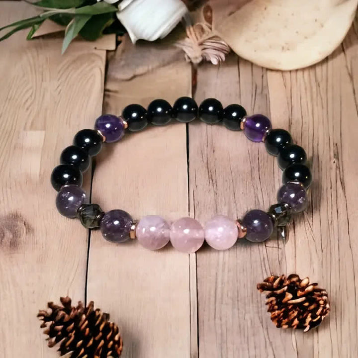 Armband aus Amethyst und Rosenquarz auf Holztisch, handgefertigter Schmuck, Natursteine.