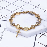 Goldenes Armband mit Kreuzanhänger, religiöses Design, runde Medaillons, modisches Accessoire.