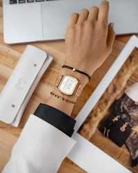 Goldene Armbanduhr und Armband mit Sternanhänger auf Hand, elegantes Schmuckdesign.