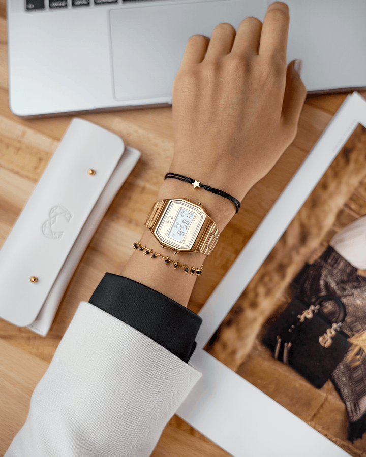 Goldene Armbanduhr und Armband mit Sternanhänger auf Hand, elegantes Schmuckdesign.