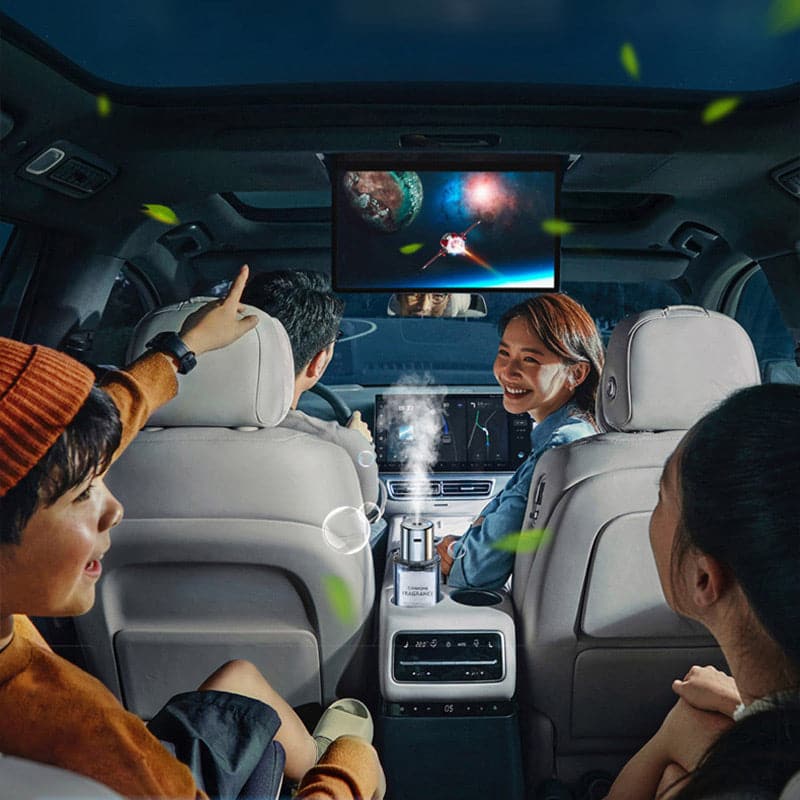 Familie im Auto mit Deckenbildschirm, Luftbefeuchter, Nachtfahrt, Unterhaltungssystem.