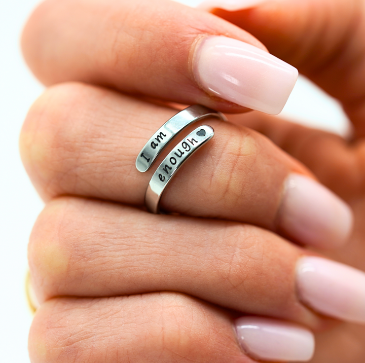 Silberner Ring mit Gravur "I am enough", getragen an Hand mit hellrosa Nagellack.