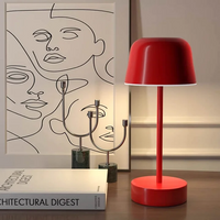 Rote Tischlampe aus Metall, modernes Design, neben Kunstwerk und Architekturzeitschrift.