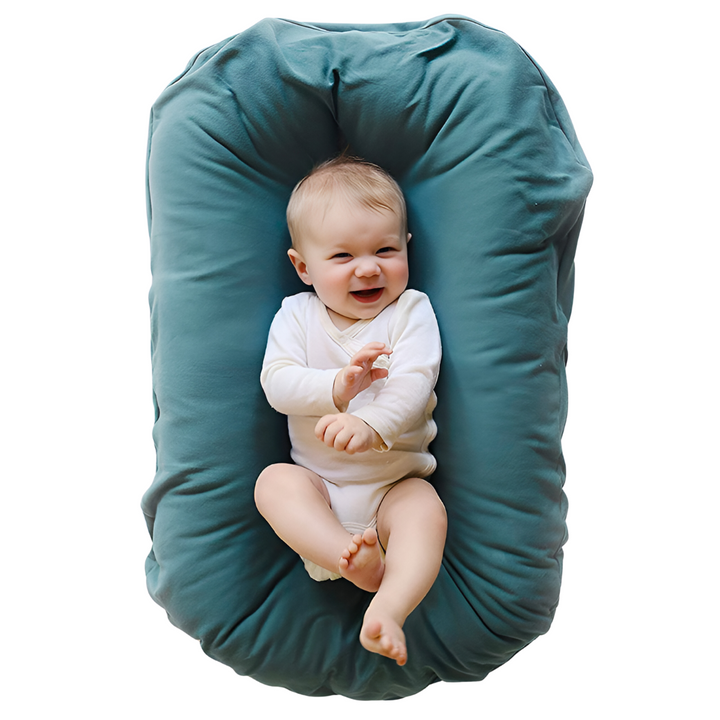 Lächelndes Baby in blauem Babynest, weiches Material, bequem, sicher, ideal für Neugeborene.