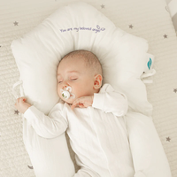Schlafendes Baby auf weißem Babynest mit Schnuller, bestickt mit "You are my beloved angel".