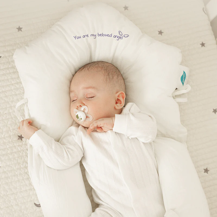 Schlafendes Baby auf weißem Babynest mit Schnuller, bestickt mit "You are my beloved angel".