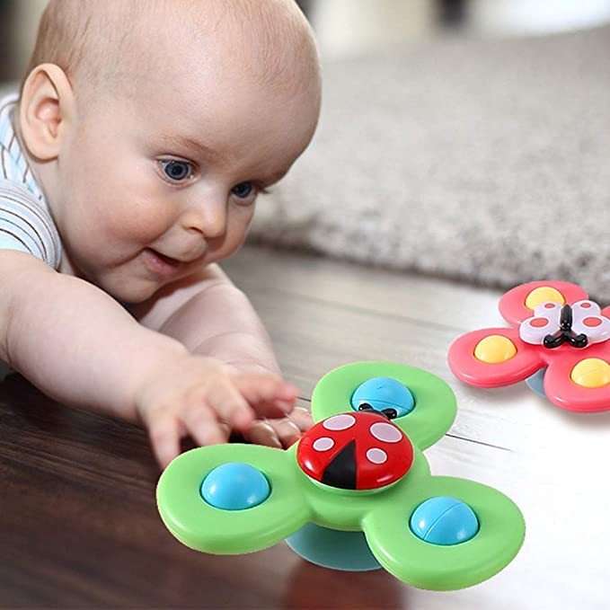 Baby spielt mit grünem Marienkäfer-Fidget-Spinner auf Holzboden, sensorisches Spielzeug.
