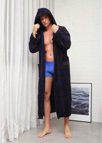 Mann im karierten Bademantel mit Kapuze, blau, Baumwolle, vor weißen Vorhängen, moderne Einrichtung.