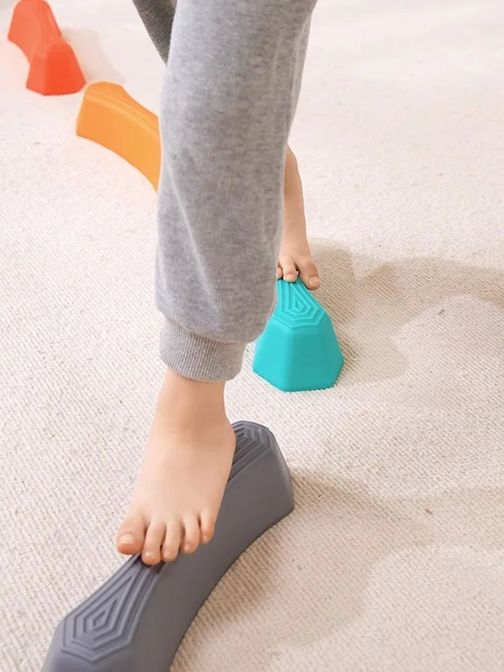 Kind balanciert auf bunten Balance-Steinen, Indoor-Spielzeug, motorische Fähigkeiten fördern.