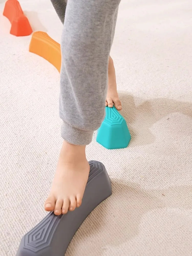 Kind balanciert auf bunten Balance-Steinen, Indoor-Spielzeug, motorische Fähigkeiten fördern.