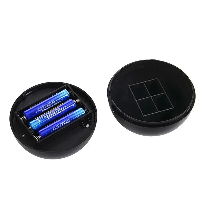 Schwarze runde Fernbedienung mit Batteriefach, drei blaue AA-Batterien, geöffnet.