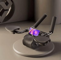 Schwarzes Bauchmuskelrad mit Griffen und Smartphone-Halterung auf grauem Hintergrund.